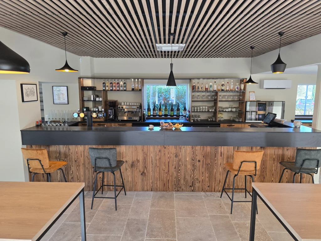 Bar aménagé par Bastien De Almeida : comptoir en bois, plan sombre et étagères murales