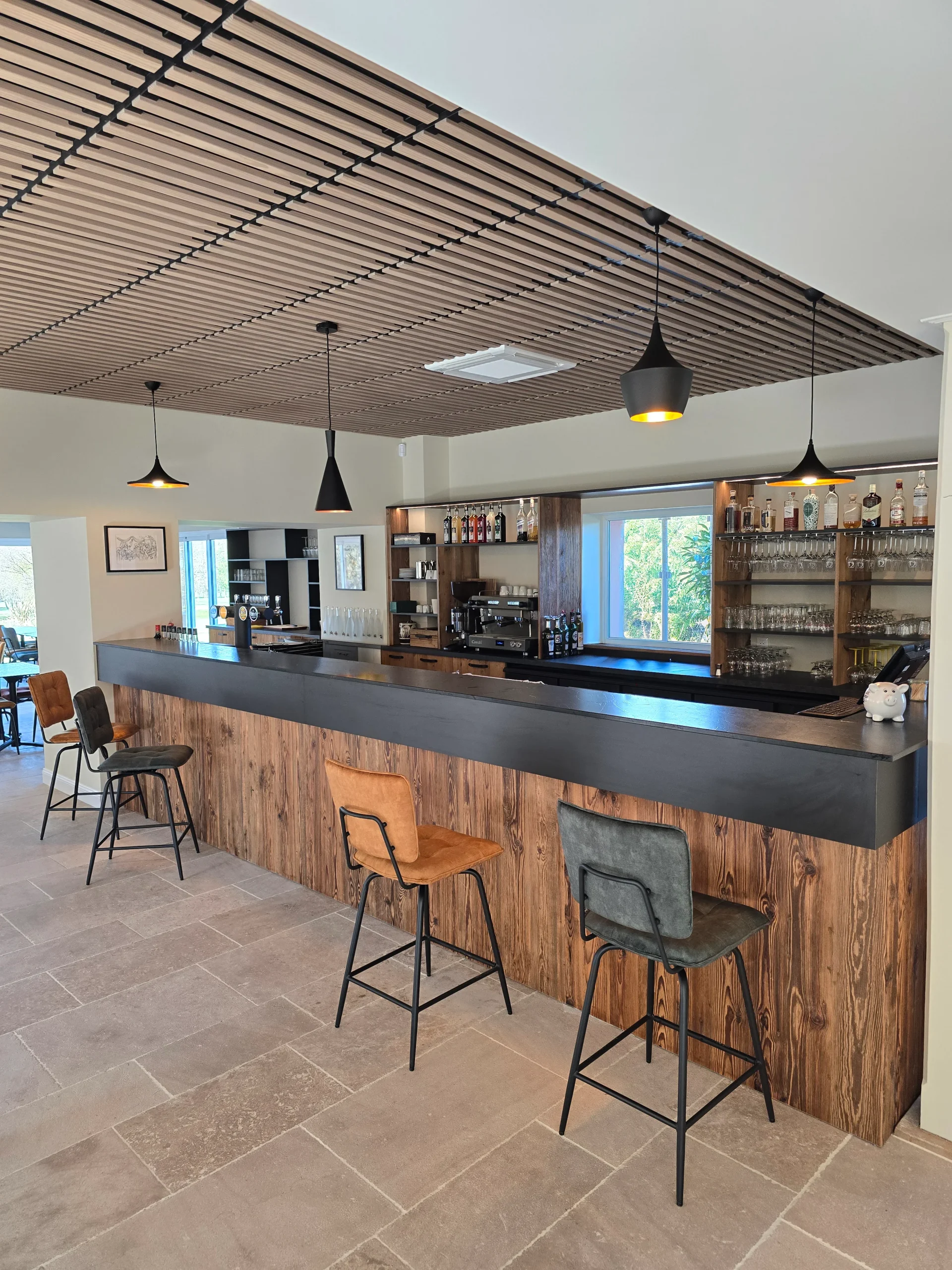 Bar en bois avec comptoir sombre, rangements et plafond en lames de bois