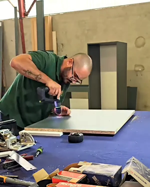 Artisan assemblant un panneau sur mesure à l’établi dans son atelier