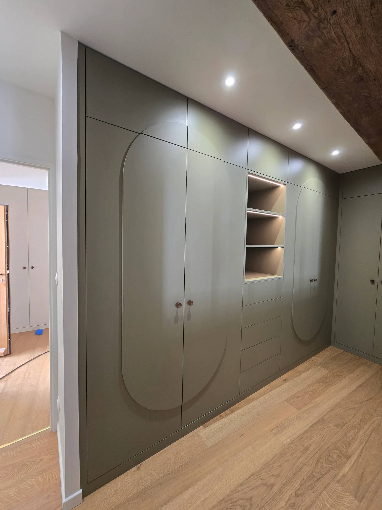 Rangements sur mesure réalisés par Bastien De Almeida : façades vertes aux motifs arrondis et niches éclairées